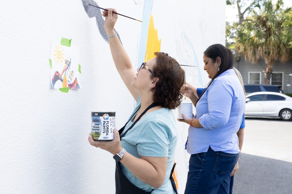 Women painting a mural on the LMCU building in St. Petersburg using Florida Paints exterior paint.